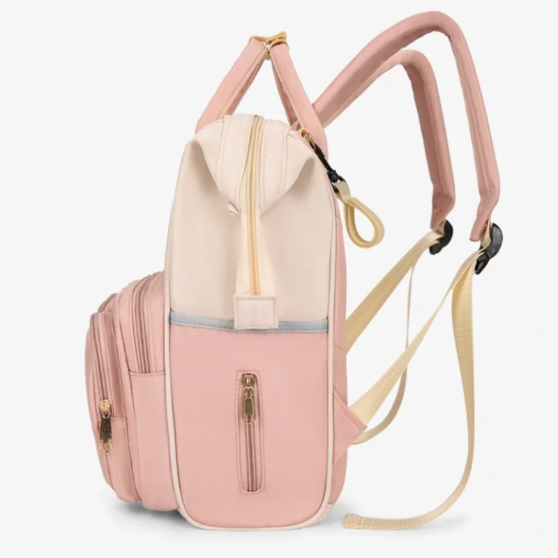 ピンクとベージュの「サイドビューがかわいい多機能軽量マザーバックパック」は、ゴールドのジッパー、調節可能なストラップ、サイドポケット、複数のコンパートメントを備えています。実用性と可愛らしさを兼ね備えた広々としたデザインで自立します。.
